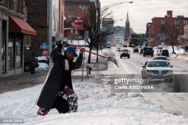 Resident digs out a bus stop on Main Street in Buffalo, New York, on December 29, 2022. - The death toll from a fierce winter storm that gripped much...