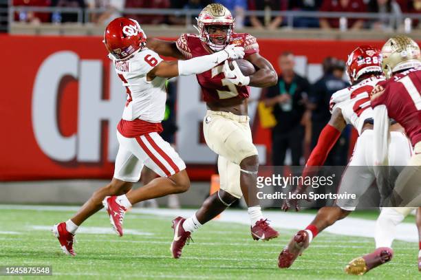 Florida State Seminoles running back Trey Benson delivers a stiff-arm to Oklahoma Sooners defensive back Trey Morrison during the Cheez-It Bowl...