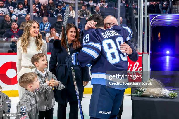 Sam Gagner of the Winnipeg Jets embraces his father, Dave, during the pre-game ceremony to commemorate his milestone 1000 career NHL games before...