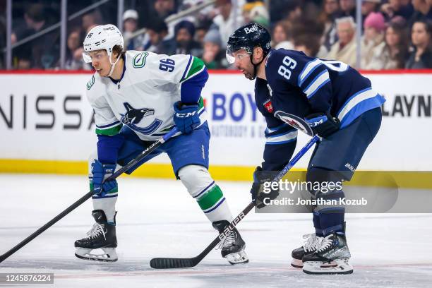 Andrei Kuzmenko of the Vancouver Canucks and Sam Gagner of the Winnipeg Jets get set during a first period face-off at the Canada Life Centre on...