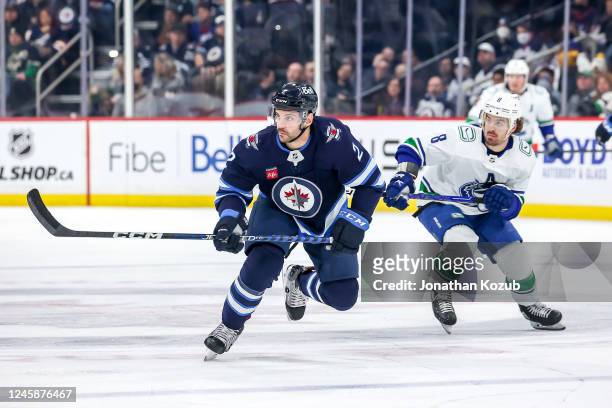 Dylan DeMelo of the Winnipeg Jets and Connor Garland of the Vancouver Canucks follow the play down the ice during first period action at the Canada...