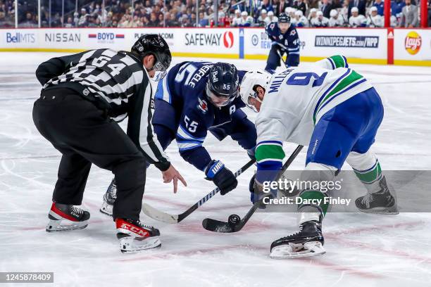 Mark Scheifele of the Winnipeg Jets and J.T. Miller of the Vancouver Canucks take a second period face-off at the Canada Life Centre on December 29,...