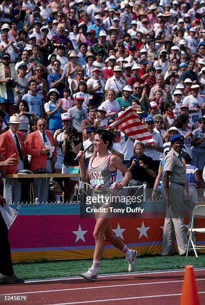 Joan Benoit of the USA carries an American flag as she takes a victory lap around the Los Angeles Memorial Coliseum following her gold medal...