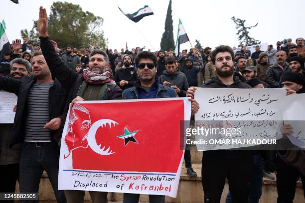 Demonstrator holds a placard representing Turkey's president devouring the Syrian opposition flag, during a rally against a potential rapprochement...