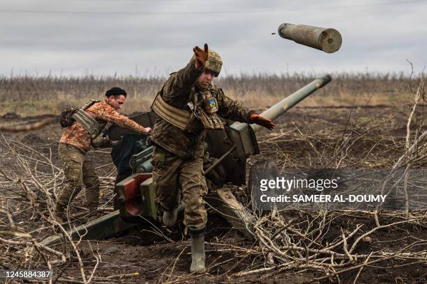 Ukrainian serviceman of an artillery unit throws an empty shell as they fire towards Russian positions on the outskirts of Bakhmut, eastern Ukraine...