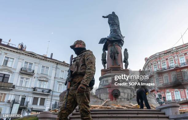 Soldier in camouflage and with a machine gun on guard duty during preparations for the demolition of the monument to Russian empress Catherine II....