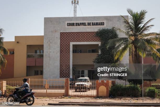Man rides his motorbike past the Court of Appeal in Bamako, where the trial of the 46 Ivorian soldiers arrested in Mali takes place on December 30,...