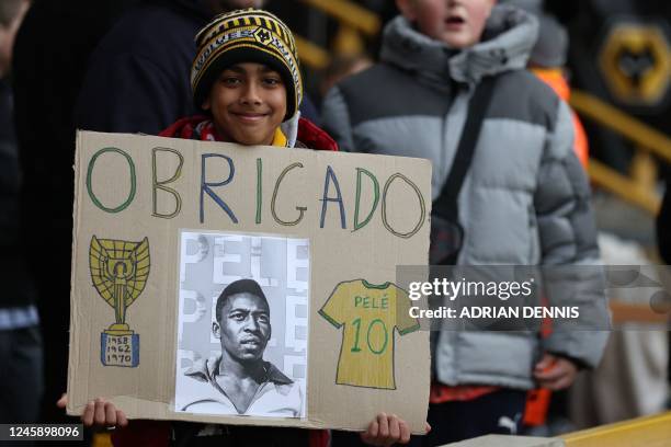 Wolves fan holds up a banner with a messge of thanks to honour Brazilian football legend Pele, who died on December 29, ahead of the English Premier...