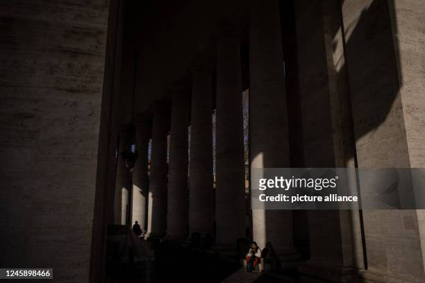 December 2022, Vatican, Vatican City: A woman sits on a column at the colonnade surrounding Saint Peter's Square. The Vatican announced that Pope...
