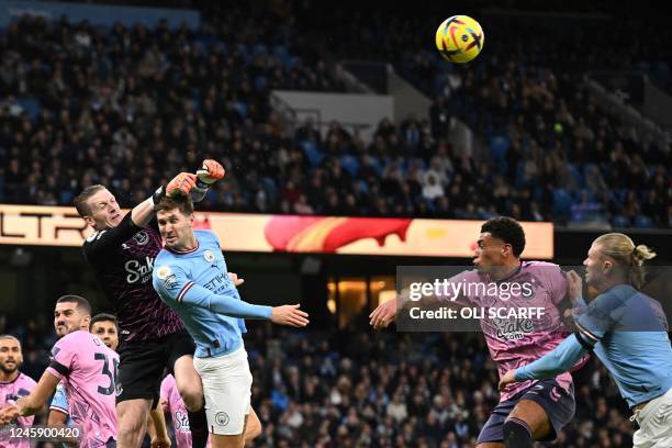 Everton's English goalkeeper Jordan Pickford punches the ball clear under pressure from Manchester City's English defender John Stones during the...