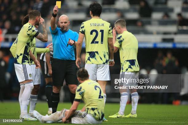 English referee Simon Hooper shows a yellow card to Leeds United's English defender Luke Ayling during the English Premier League football match...