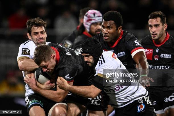Lyon's Australian inside centre Kyle Godwin is tackled by Brives Argentinian fly-half Nicolas Sanchez and Brive's French full-back Thomas Laranjeira...