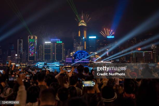 People watching Fireworks display over building on Hong Kong Island, 2023 display on the Hong Kong Convention and Exhibition Center to mark the...