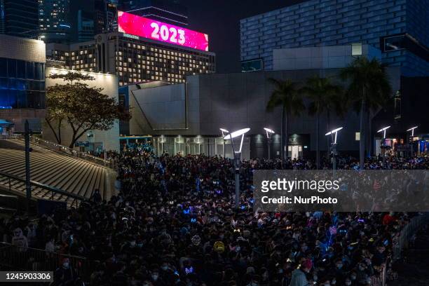 General view showing people in Tsim Sha Tusi before the countdown to 2023 and a electronic billboard on top of a building displaying 2023 on it on...
