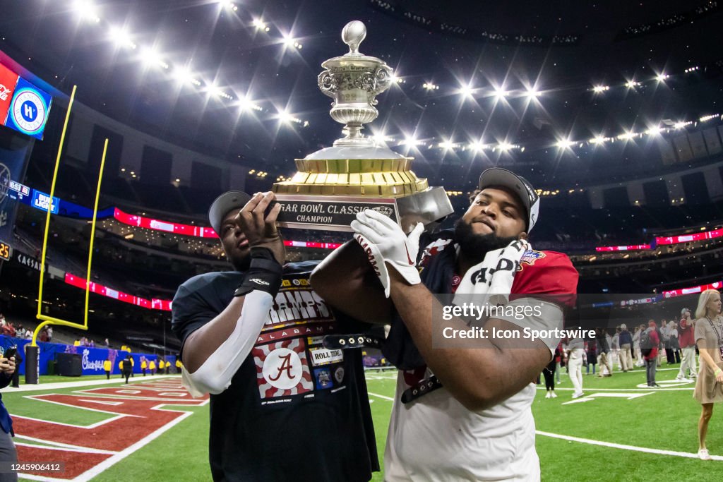 A couple of members of the Crimson Tide carry the trophy back to the A couple of members of the Crimson Tide carry the trophy back to the