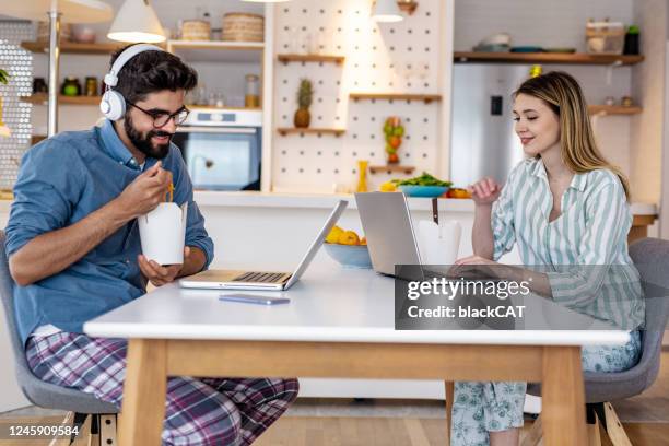 a young couple working from home on their laptops in new dress code - dress code stock pictures, royalty-free photos & images