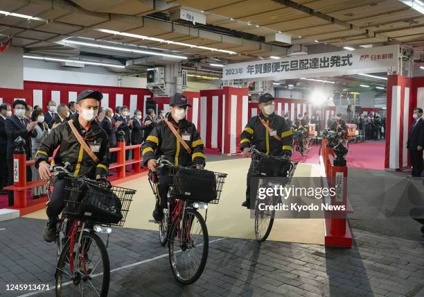 Postal workers depart Tokyo's Nihombashi post office on Jan. 1 to deliver New Year's greeting cards following a ceremony attended by communications...