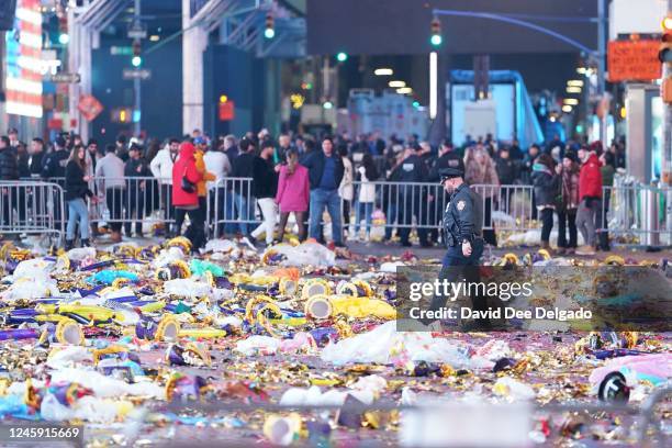 Police officer walks through garbage left behind by revealers at Times Square after the New Year celebrations on January 1, 2023 in New York City....