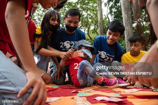 Family plays a money game at Rizal Park in Manila, as they celebrate the New Year on January 1, 2023.