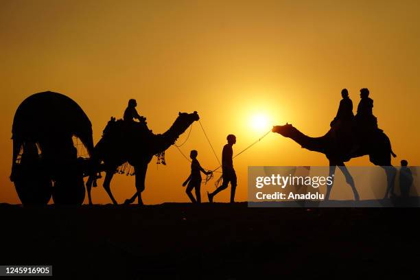 Silhouettes of Indian tourists are seen as they enjoying camel safari during the year's last sunset in Desert of Pushkar, Rajasthan, India on...