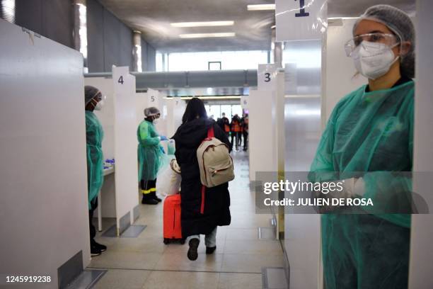 Traveller of a flight from China walks through the COVID-19 testing booths at the Paris-Charles-de-Gaulle airport in Roissy, outside Paris, on...