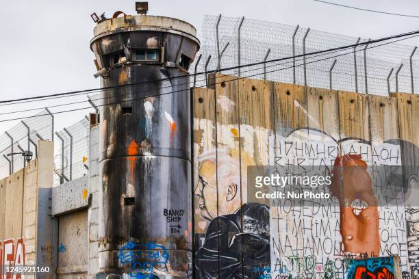 View on a watchtower and Donald Trump street art graffiti on the Israeli separation West Bank Wall in Bethlehem, Palestine on December 28, 2022.