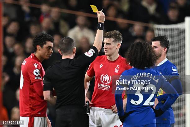English referee Peter Bankes shows a yellow card to Nottingham Forest's English midfielder Ryan Yates during the English Premier League football...