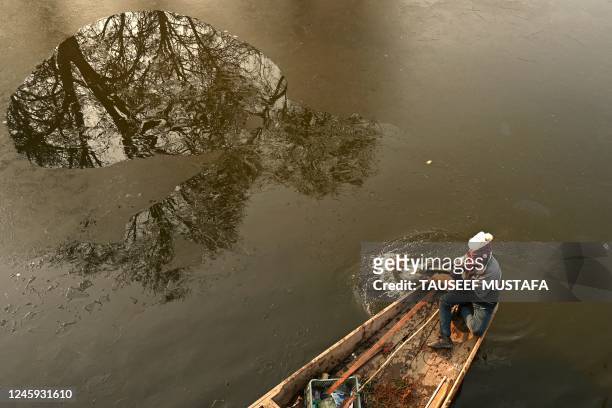 Boatman uses an oar to break the ice layer along the interiors of Dal Lake on a cold winter morning in Srinagar on January 2, 2023.