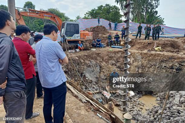 Rescuers look down into the site of where a 10-year-old boy is thought to be trapped in a 35-metre deep shaft at a bridge construction area in...