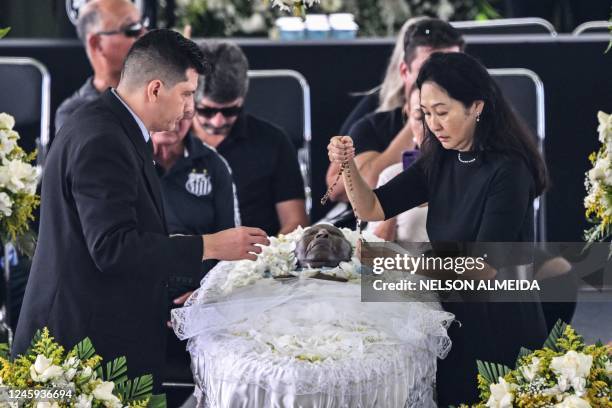 The wife of late Brazilian football legend Pele, Marcia Aoki , places a rosary on his coffin during his wake at the Urbano Caldeira stadium in...