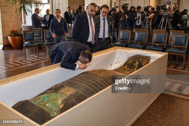 Mostafa Waziri, the head of Egypt's Supreme Council of Antiquities, uses a magnifying glass to inspect an ancient Egyptian wooden sarcophagus being...