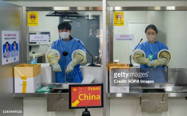 Quarantine officials seen preparing for a PCR test for travelers arriving from China in COVID-19 testing station at Incheon International Airport,...