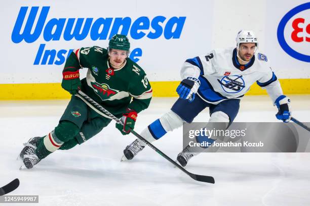 Sam Steel of the Minnesota Wild and Dylan DeMelo of the Winnipeg Jets keep their eyes on the play during third period action at Canada Life Centre on...