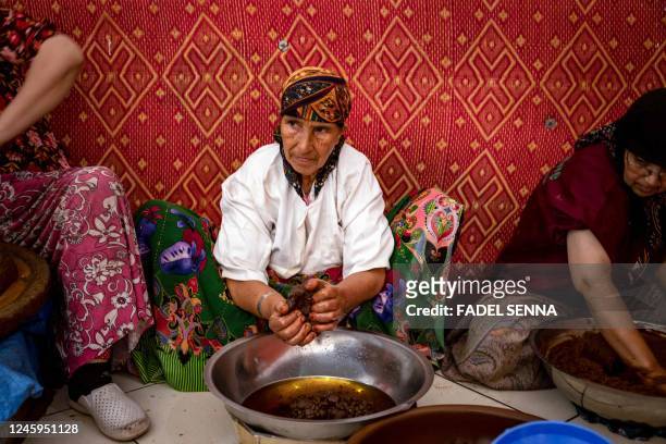 Women squeeze oil out of a paste made from crushed Argan nuts, near Morocco's western Atlantic coastal city of Essaouira, on October 15, 2022. -...