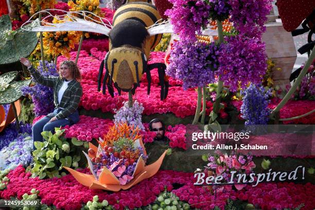 Pasadena, CA A participant waves while a float driver peeks his head out from underneath a large bee and between flower beds while steering the...