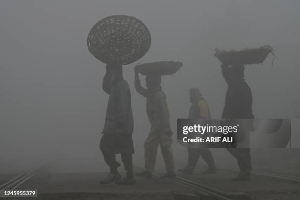 Labourers arrive at fruit market amid smoggy and foggy conditions early in the morning in Lahore on January 3, 2023.