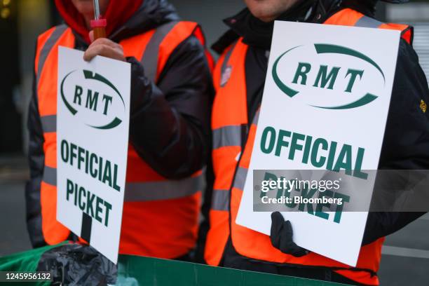 Members of the National Union of Rail, Maritime and Transport hold placards that read "RMT Official Picket" on a picket line during strike action...
