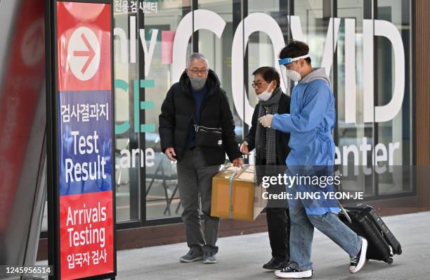 Health worker guides travellers arriving from China in front of a Covid-19 testing centre at Incheon International Airport, west of Seoul on January...