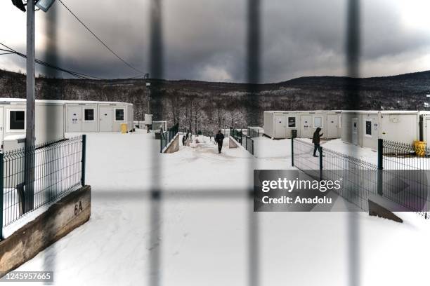 People walk among container shelters in Bihac, Bosnia and Herzegovina on December 23, 2022. Passing through the mountains is not easy not only...