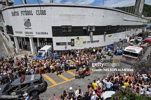 Fans of the late Brazilian football star Pele gather outside the Urbano Caldeira stadium as a firetruck transports Pele's coffin to the Santos'...