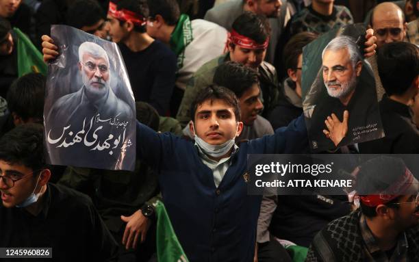 An Iranian carries the portraits of slain Iranian commander Qasem Soleimani and Iraqi commander Abu Mahdi al-Muhandis during a ceremony in the...