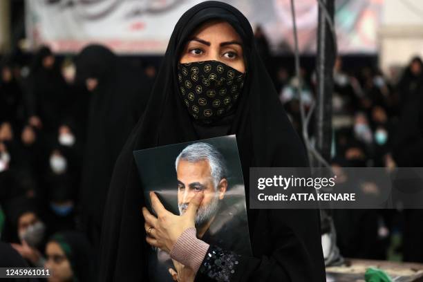 An Iranian carries the portrait of slain Iranian commander Qasem Soleimani during a ceremony in the capital Tehran, on January 3 to commemorate the...