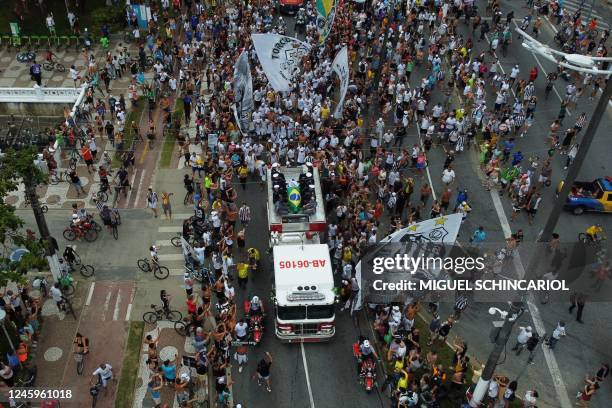 In this aerial picture fans of the late Brazilian football star Pele gather on the street as a firetruck transports Pele's coffin to the Santos'...