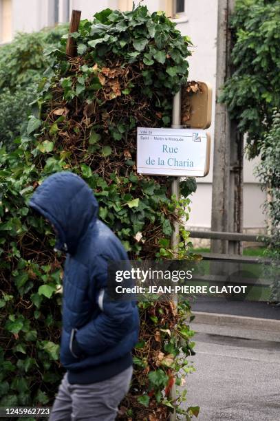 Person walks on November 4, 2011 in Saint-Martin-le-Vinoux, central France, past a road sign that is covered up with a sticker to rename it "Charia...