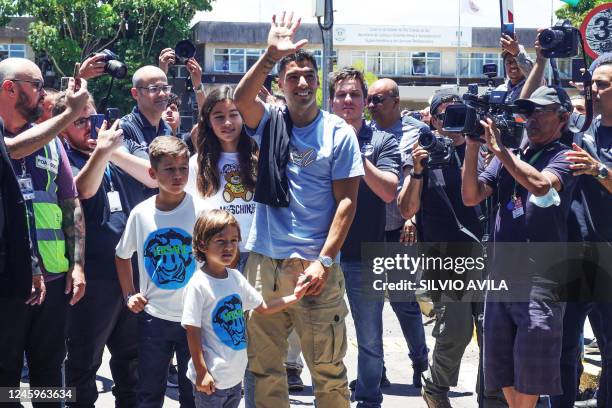 Uruguayan forward Luis Suarez, accompanied by his sons and daughter, greets fans outside the Salgado Filho International Airport in Porto Alegre,...