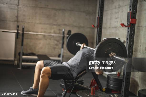 sports man doing bench press, athlete during training in professional gym, lifting weights for biceps, pectorals and back muscles - bench press stock pictures, royalty-free photos & images
