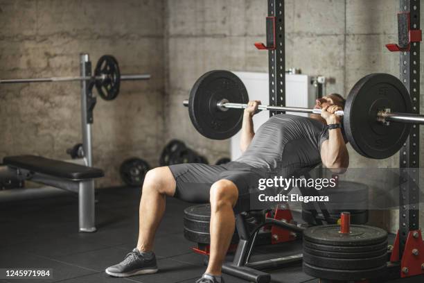 sportmann macht bankdrücken, athlet beim training in professionellen fitness-studio, gewichte für bizeps, brust- und rückenmuskulatur - bench press stock-fotos und bilder