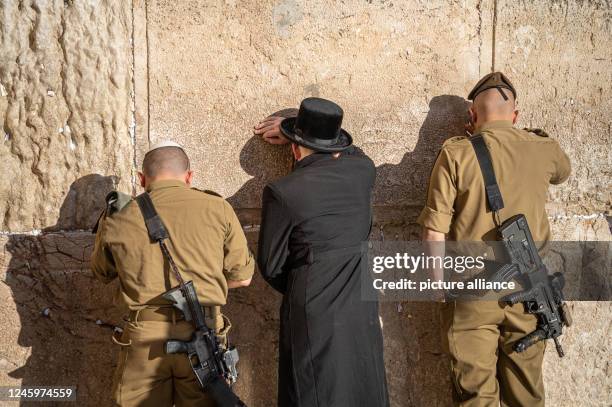 December 2022, Israel, Jerusalem: An ultra-Orthodox believer and two armed soldiers pray on the Temple Mount in Jerusalem at the Wailing Wall. Photo:...