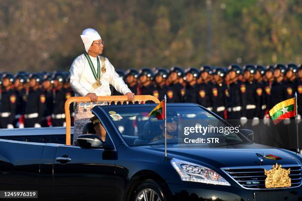Myanmar's military chief Min Aung Hlaing stands in a car as he oversees a military display at a parade ground to mark the country's Independence Day...