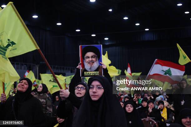 Supporters of the Lebanese Shiite movement Hezbollah wave national and party flags during a gathering to attend a televised speech by the group's...